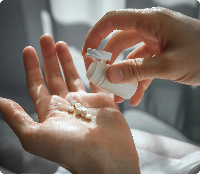 Hand pouring hair loss medication tablets into a patient's palm